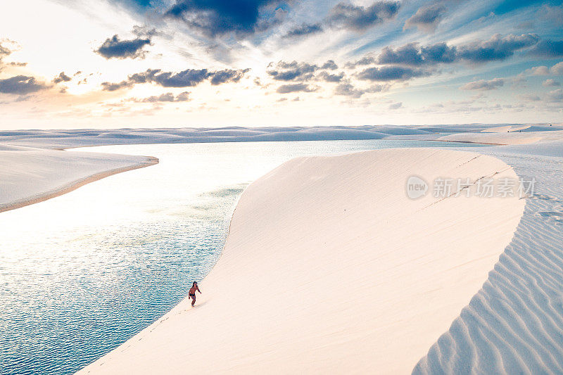 一个年轻人正在攀登Lençois Maranhenses的沙丘